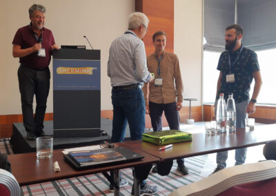 The Best Poster Award goes to Artur Jurkowski (right) and Marcin Wójcik. In the background András Poppe, the Therminic 2023 Programme Chair